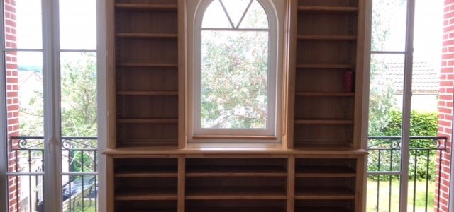 Bibliothèque sur mesure en châtaignier venant encadrer trois fenêtres