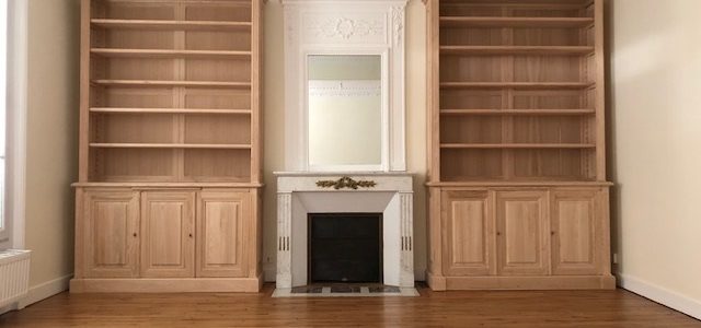 Paire de bibliothèques venant encadrer une cheminée en marbre blanc
