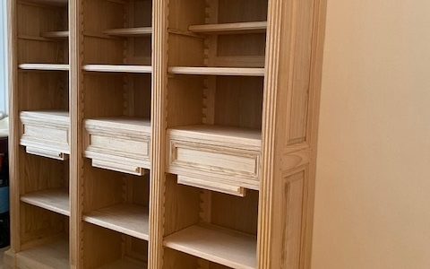 Bibliothèque en bois naturel de style Louis XVI reposant sur une plinthe à ressauts
