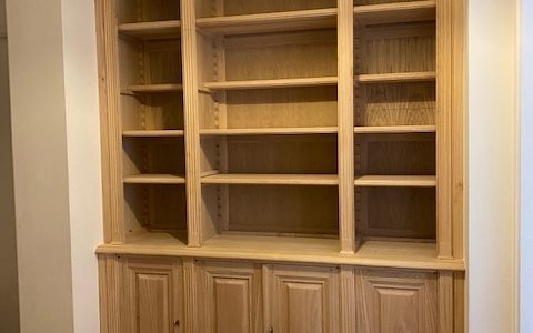 Bibliothèque cachant tuyaux de chauffage et trappe de canalisation