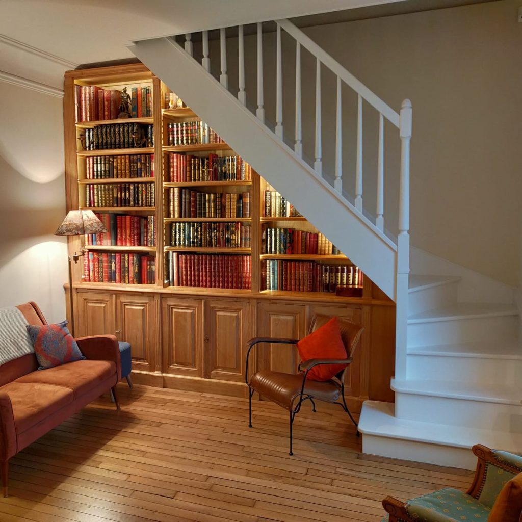 Bibliothèque intemporelle en bois naturel sous un escalier