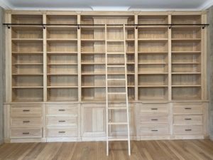 Bibliothèque de parquet en bois naturel venant coffrer un large conduit de cheminée