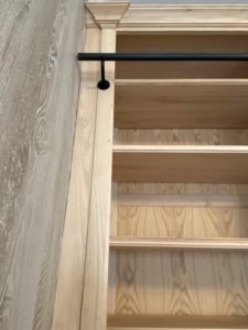 Bibliothèque de parquet en bois naturel venant coffrer un large conduit de cheminée