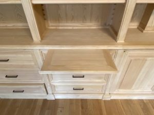 Bibliothèque de parquet en bois naturel venant coffrer un large conduit de cheminée