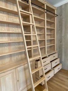 Bibliothèque de parquet en bois naturel venant coffrer un large conduit de cheminée