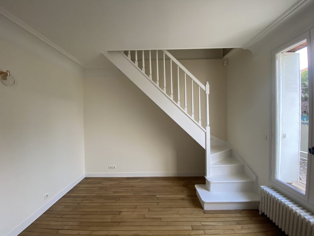 Bibliothèque intemporelle en bois naturel sous un escalier