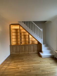 Bibliothèque intemporelle en bois naturel sous un escalier