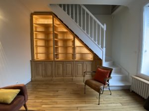 Bibliothèque intemporelle en bois naturel sous un escalier