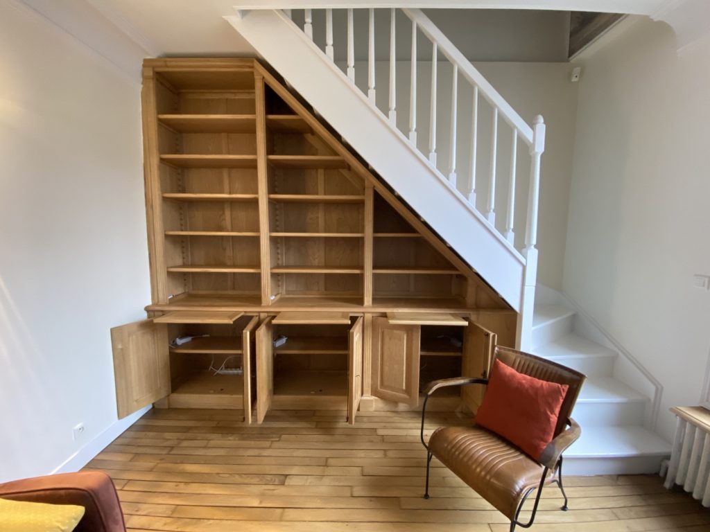 Bibliothèque intemporelle en bois naturel sous un escalier