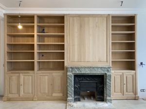 Bibliothèques intemporelle en bois naturel encadrant une cheminée en marbre vert de mer d’époque XIX eme