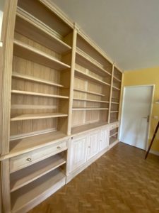 Bibliothèque formant bureau en bois naturel du sol au plafond et de mur à mur