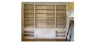 Bibliothèque formant bureau en bois naturel du sol au plafond et de mur à mur