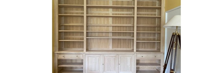 Bibliothèque formant bureau en bois naturel du sol au plafond et de mur à mur