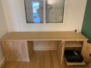 Télétravail sur un grand bureau et sa bibliothèque en bois naturel