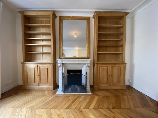 Paire de bibliothèques en bois naturel venant encadrer une cheminée