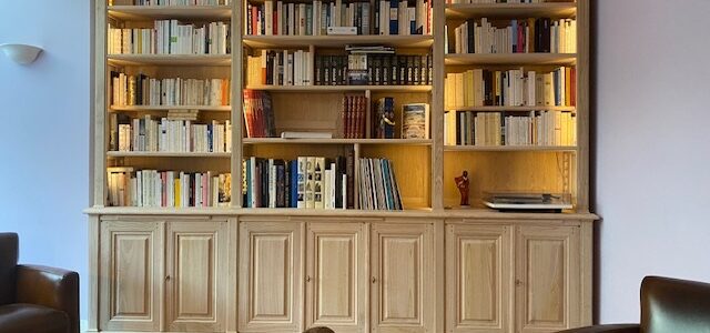 Bibliothèque en bois naturel ouvrante en façade par sept portes surmontées par trois tablettes de lecture