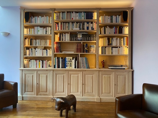 Bibliothèque en bois naturel ouvrante en façade par sept portes surmontées par trois tablettes de lecture