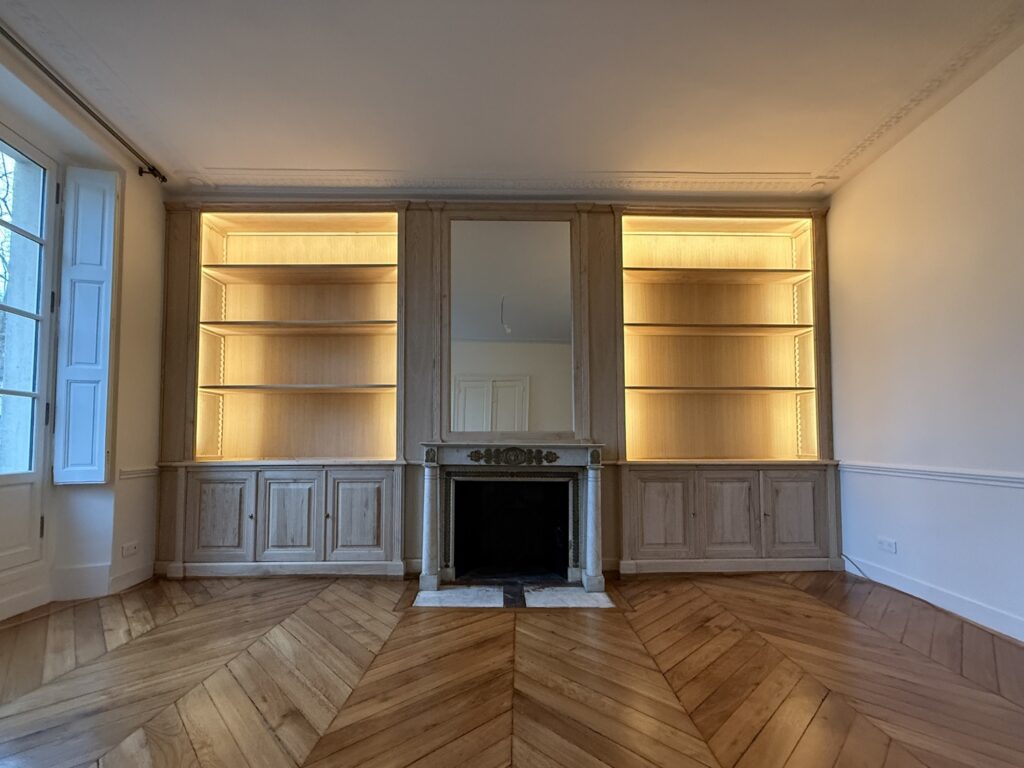 Mur en boiseries autour d’une cheminée en marbre et bibliothèques intégrées