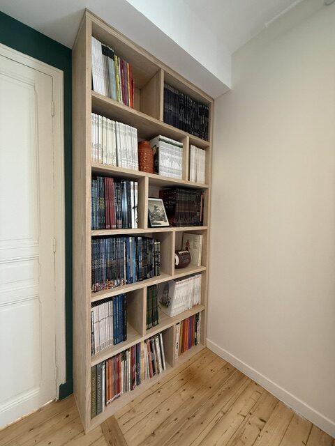 Bibliothèque sur mesure en châtaignier massif pour BD, installée à côté d’une porte sur parquet ancien